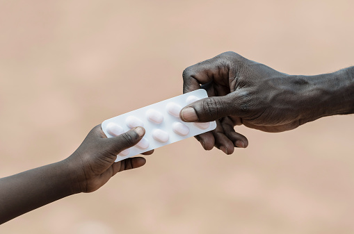 Curing Disease Symbol: African Man Giving Pills to Child